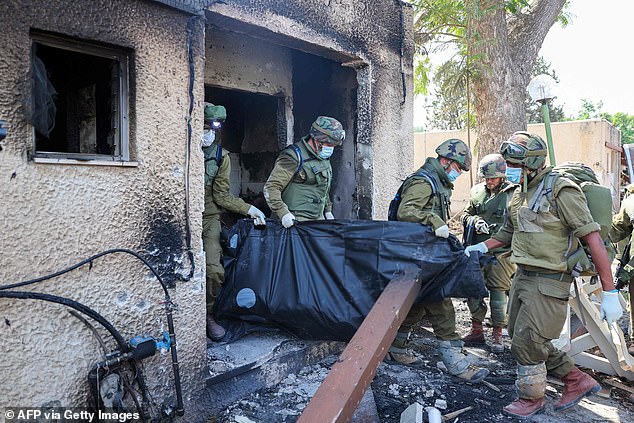 Hamas terrorists ‘beheaded babies during kibbutz slaughter where 40 young children were killed’: IDF soldiers reveal families were killed in their bedrooms – ‘not in war, not a battlefield… a massacre’ Israeli soldiers remove the body of a compatriot, killed during an attack by Hamas terrorists in Kfar Aza, on Tuesday