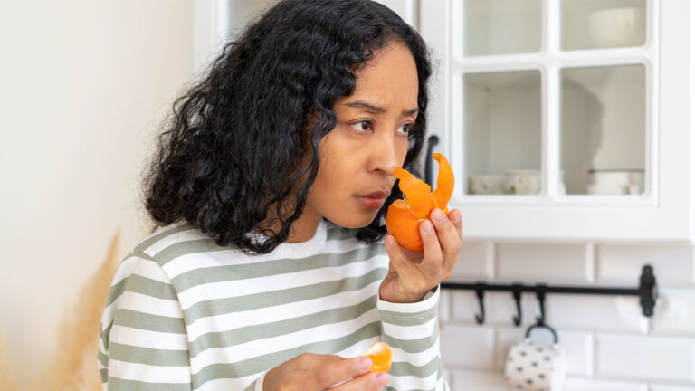 50 years ago, scientists suspected that lost sense of smell could be restored A woman sniffs a half-peeled tangerine in her kitchen.
