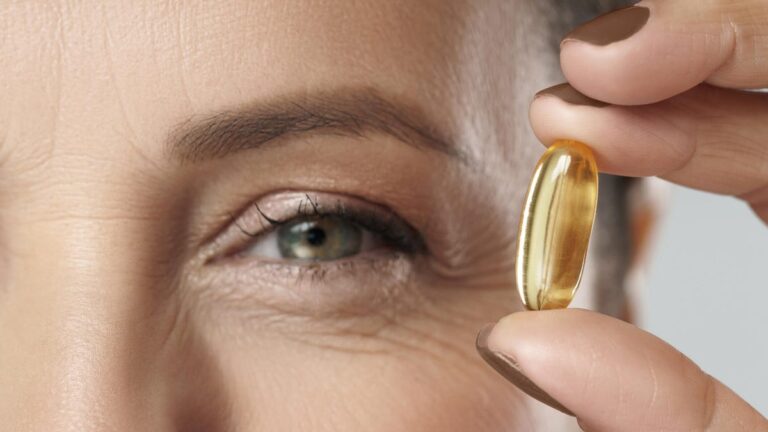 6 Best Vitamins and Supplements for Healthy Eyes A middle aged woman hoping a fish oil pill next to her eye