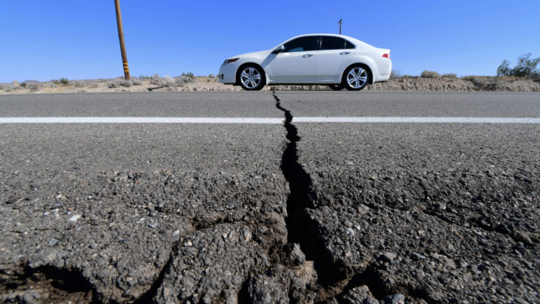 Where are U.S. earthquakes most likely? A photo of a car driving over a crack on a highway.