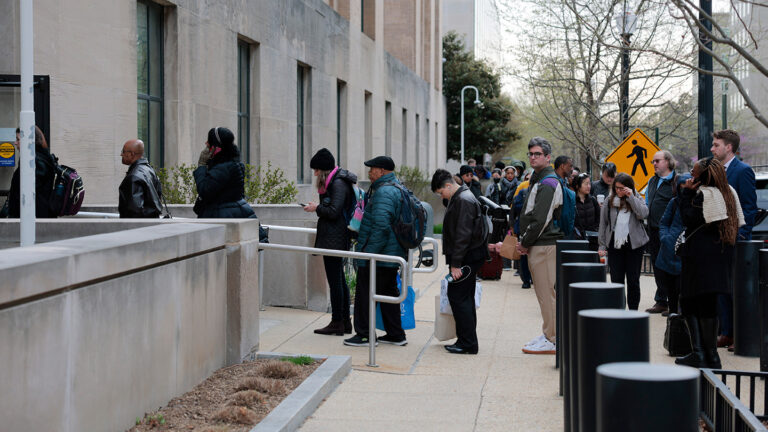 How U.S. public health cuts could raise risks of infectious diseases Lines of people stand waiting to get into a big gray federal building.
