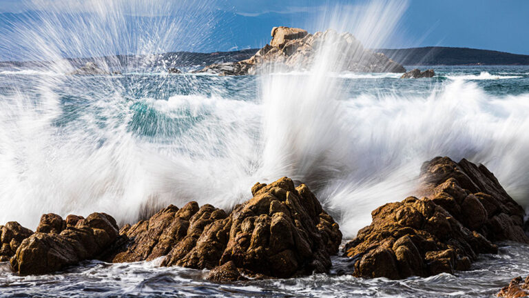 Micro-sparks between water droplets may have started life on Earth a photo of ocean water hitting rocks at a shoreline and spraying water vertically into the air in a white sheet