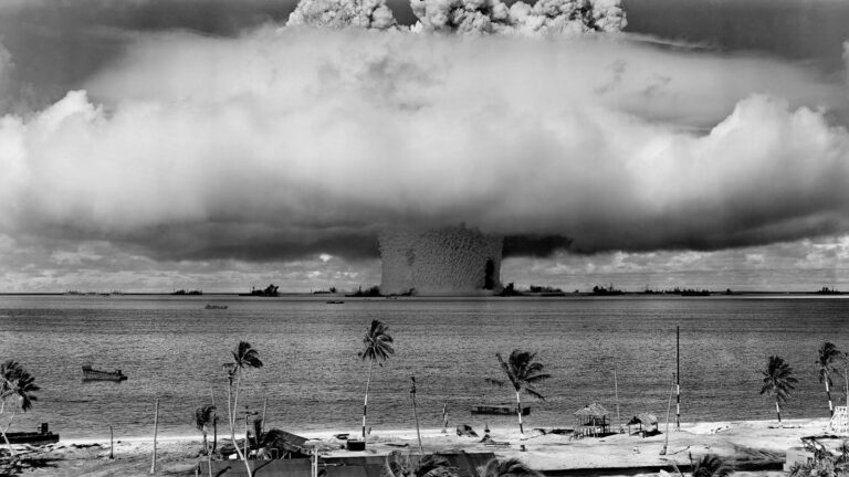 Nuclear weapons tests many decades ago have left a radioactive legacy a giant mushroom cloud billows out from Bikini atoll, as seen from a nearby beach